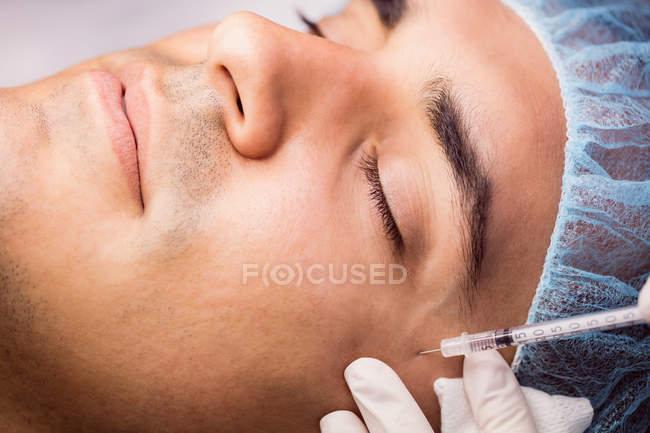 Hombre que recibe inyección de botox en la cara en la clínica - foto de stock