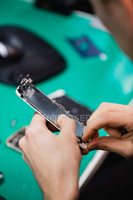 Close-up de homem reparando telefone celular no centro de reparação — Fotografia de Stock