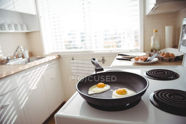 Close-up de ovos fritos em uma panela de ato de fritar na cozinha — Fotografia de Stock