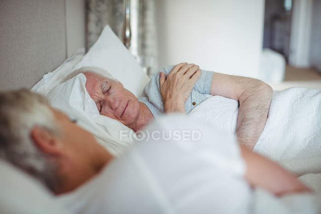 Старшая пара спит на кровати в спальне — стоковое фото