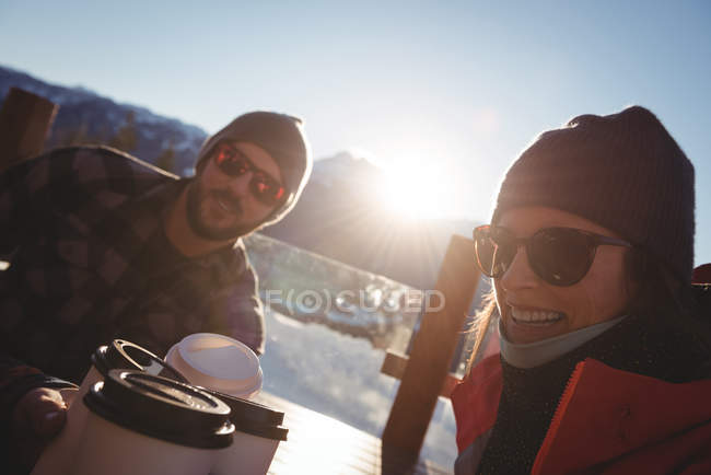 Smiling skier couple having coffee in ski resort during winter — Stock Photo