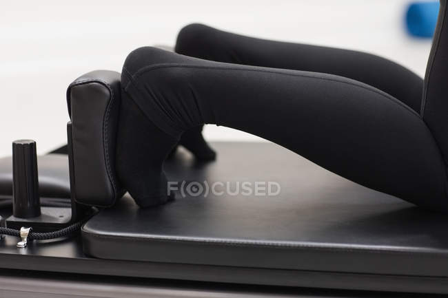 Close-up of feet of woman exercising on reformer in gym — Stock Photo