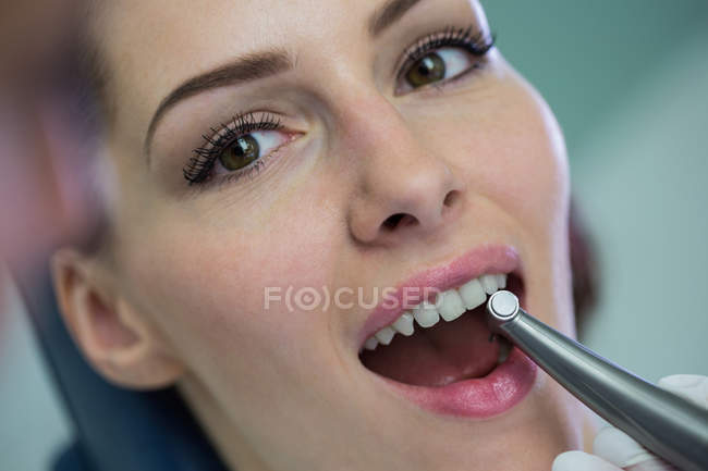 Dentista examinando uma paciente com ferramentas na clínica odontológica — Fotografia de Stock