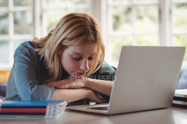 Schöne Frau entspannt sich am Tisch, während sie zu Hause Laptop im Wohnzimmer benutzt — Stockfoto