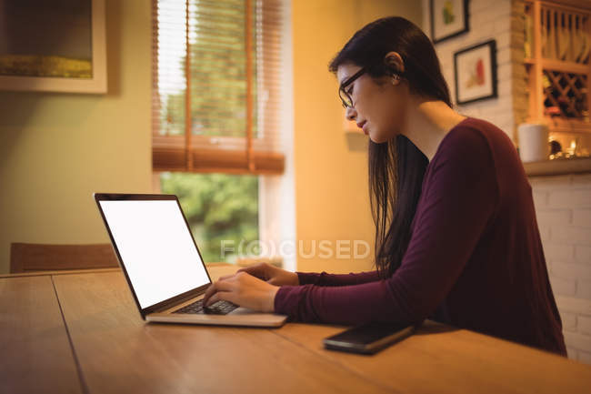 Donna che utilizza il computer portatile sul tavolo in soggiorno a casa — Foto stock