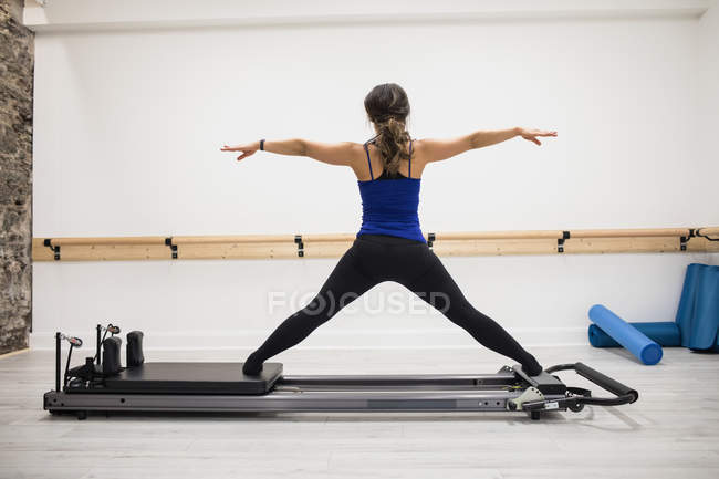 Rückansicht einer Frau, die im Fitnessstudio auf einem Reformer trainiert — Stockfoto