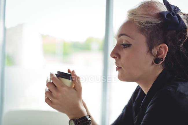 Woman holding disposable coffee cup in cafe — Stock Photo