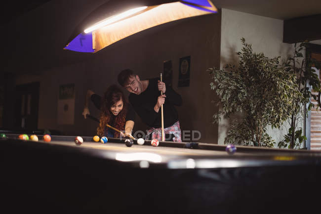 Молодая счастливая пара играет в бильярд в баре — стоковое фото