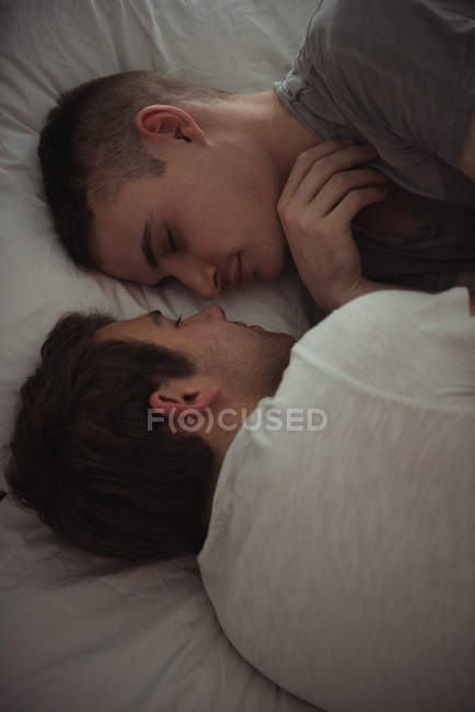 Gay couple sleeping face to face on bed in bedroom — Stock Photo