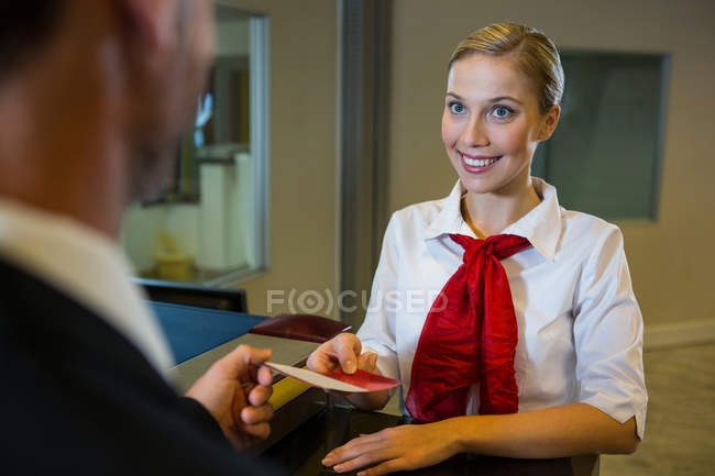 Pessoal feminino dando cartão de embarque para o empresário no check-in mesa — Fotografia de Stock
