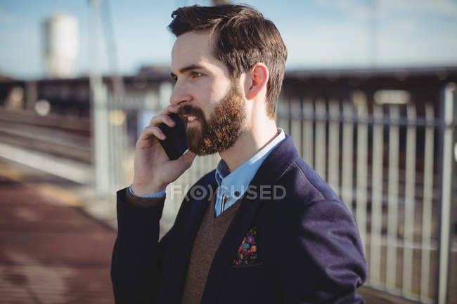 Empresário falando no celular na estação ferroviária — Fotografia de Stock
