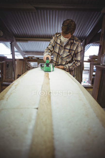 Man using modified planer in surfboard workshop — Stock Photo