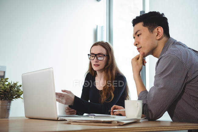 Dirigeants d'entreprise discutant sur ordinateur portable au bureau — Photo de stock