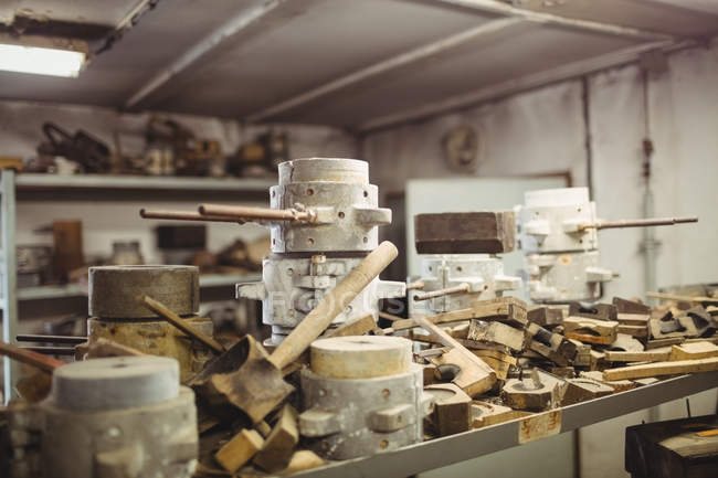 Moldes de metal y madera para soplado de vidrio dispuestos en el estante en la fábrica de soplado de vidrio - foto de stock