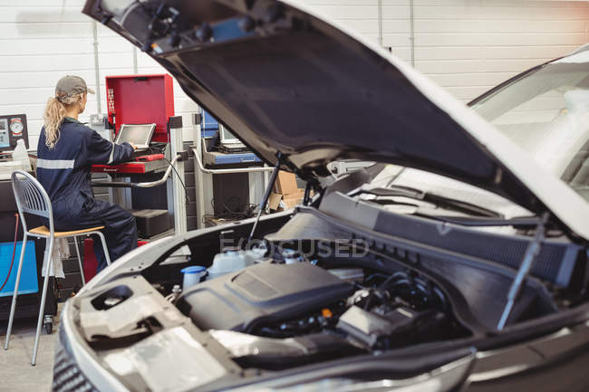 Mecânico feminino usando laptop na garagem de reparação — Fotografia de Stock