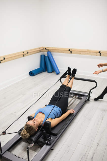 Mulher se exercitando em equipamentos reformadores no ginásio — Fotografia de Stock