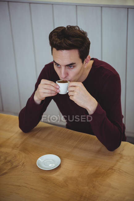 Homem tomando café enquanto sentado em uma cafeteria — Fotografia de Stock