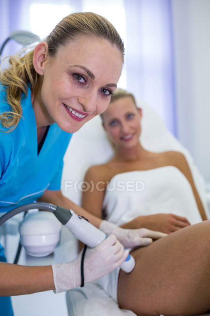 Mujer que recibe tratamiento de depilación láser en el muslo en el salón de belleza - foto de stock