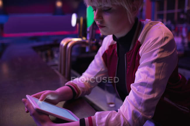 Female bartender using digital tablet at counter in bar — Stock Photo