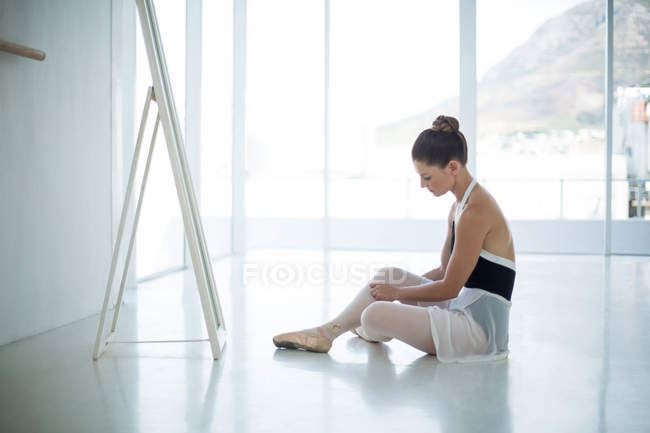 Балерина отдыхает на полу в балетной студии — стоковое фото