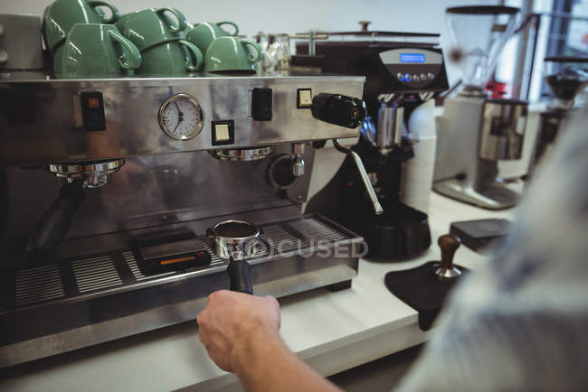 Sección media del hombre preparando café en la máquina de café en la cafetería - foto de stock