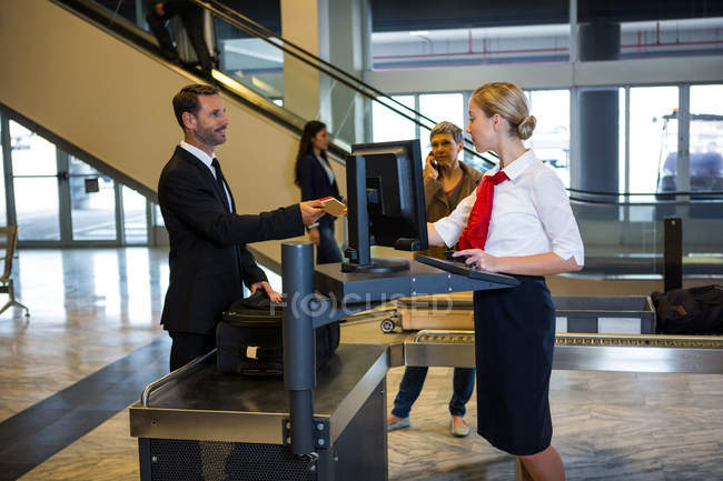 Personal femenino que interactúa con los pasajeros en la terminal del aeropuerto - foto de stock