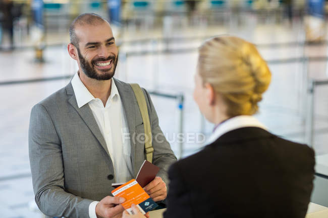 Flugbegleiter reicht Pendlern am Schalter im Flughafenterminal die Bordkarte — Stockfoto