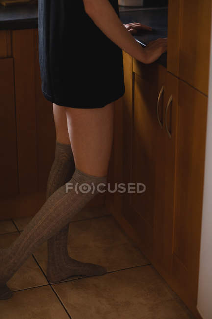 Sección baja de la mujer de pie en la cocina - foto de stock