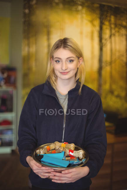 Portrait of woman holding bowl of dog bones in shop at dog care center — Stock Photo