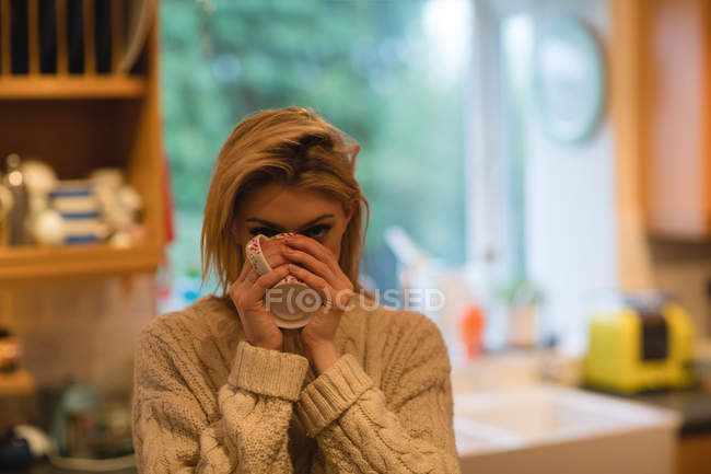 Жінка має каву на кухні вдома — стокове фото
