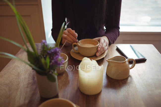Frau rührt Kaffee in einer Tasse im Café um — Stockfoto