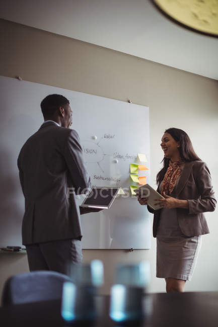 Бізнесмен обговорює на білій дошці з колегою в офісі — стокове фото