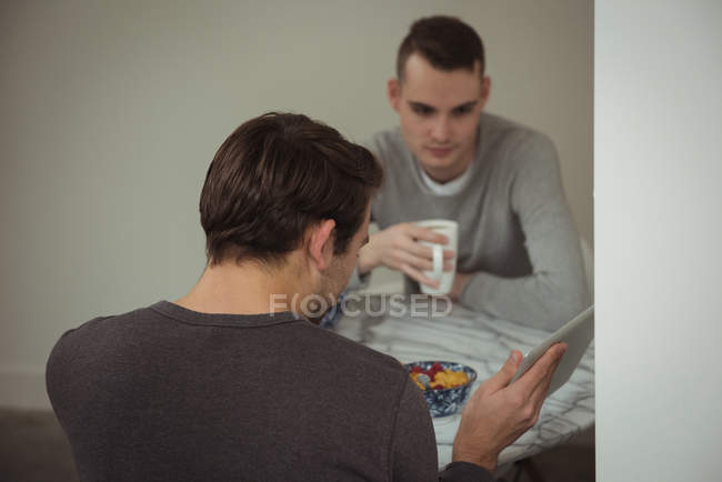 Гей-пара дивиться на цифровий планшет під час сніданку вдома — стокове фото