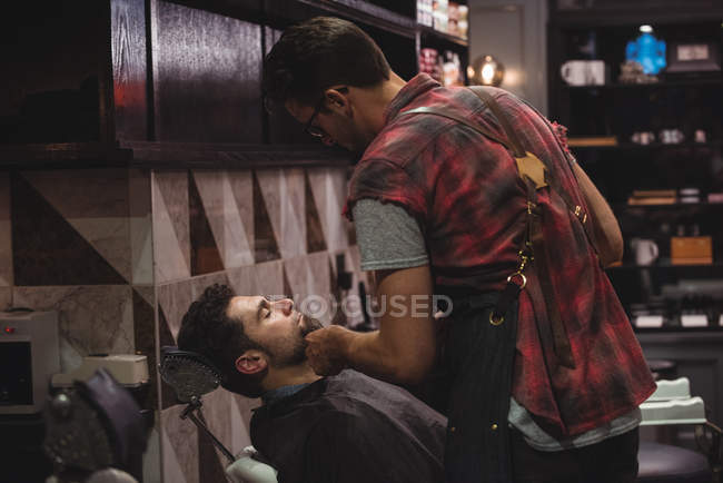 Man getting beard shaved in barbershop — Stock Photo