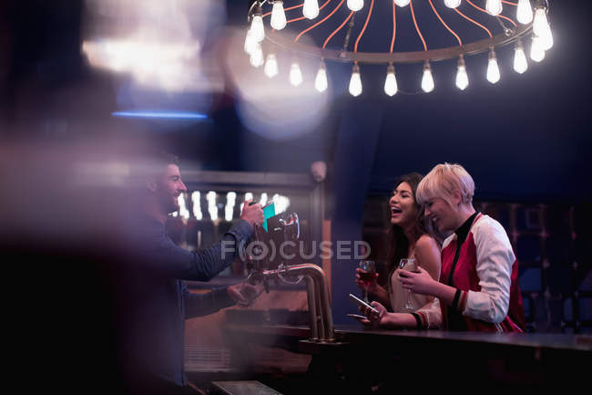 Barkeeper interagiert mit schönen Frauen am Tresen in der Bar — Stockfoto