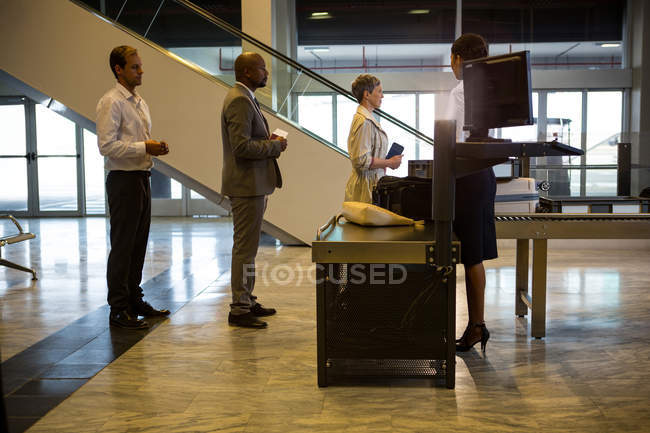 Passageiros esperando na fila em um balcão de check-in com bagagem dentro do terminal do aeroporto — Fotografia de Stock