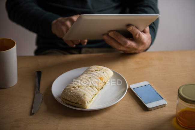Meados da seção do homem usando tablet digital em casa — Fotografia de Stock