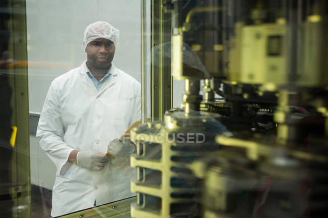 Male worker seen through machinery in juice factory — Stock Photo