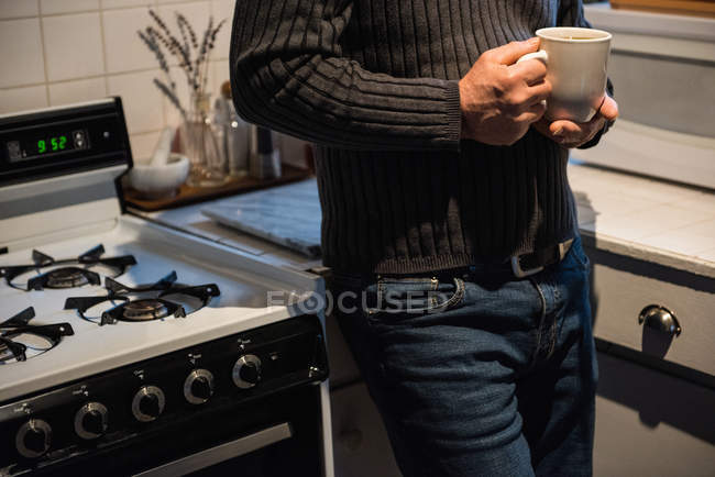 No meio da seção do homem segurando uma xícara de café em casa — Fotografia de Stock