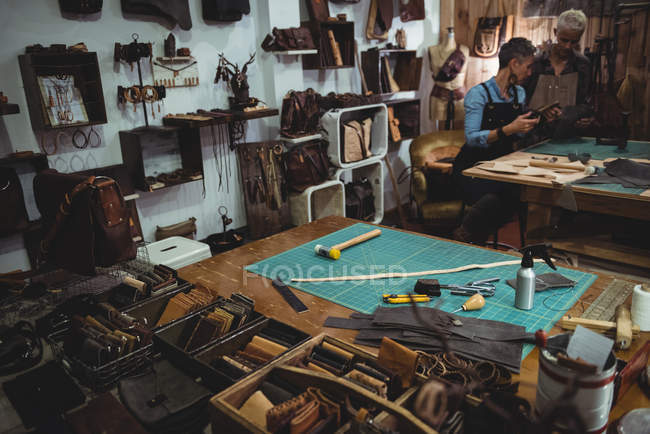 Craftswomen discussing over leather bag in workshop — Stock Photo