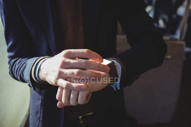 Mid-section of businessman using smartwatch while travelling in train — Stock Photo