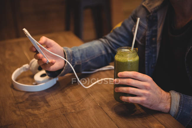 Mid section of man using mobile phone while having juice in cafe — Stock Photo