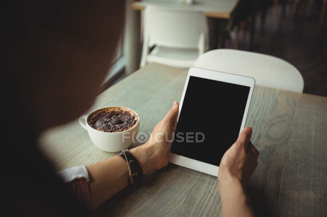 Woman using digital tablet while having cup of coffee in cafe — Stock Photo