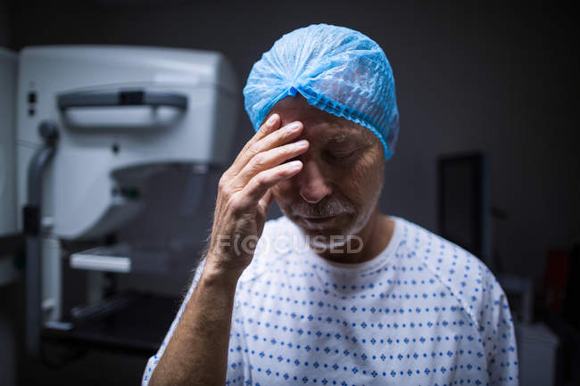 Paciente triste con la mano en la cabeza en la sala de rayos X en el hospital - foto de stock