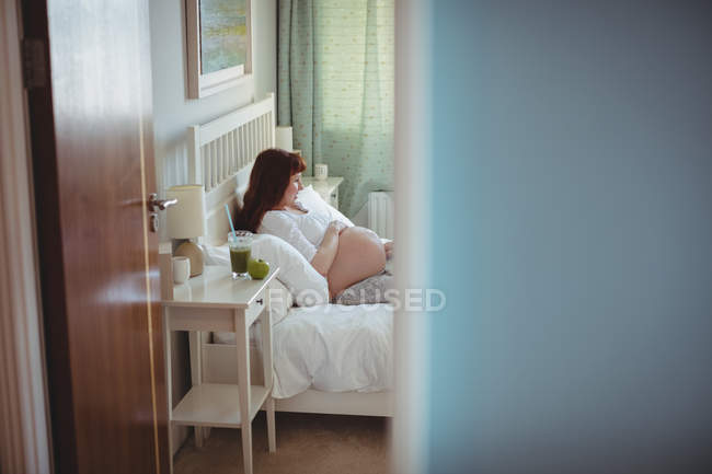Femme enceinte se détendre sur le lit dans la chambre — Photo de stock