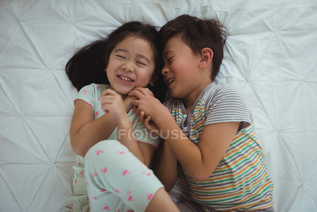 Hermanos jugando en el dormitorio en casa - foto de stock