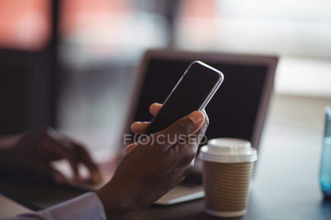 Крупный план бизнесмена с помощью мобильного телефона в офисе — стоковое фото