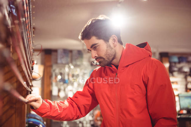 Hombre guapo seleccionando bastón de esquí en una tienda - foto de stock