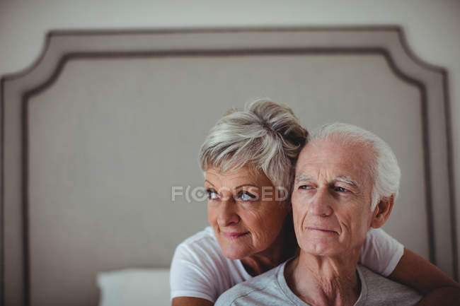 Seniorin umarmt älteren Mann auf Bett im Schlafzimmer — Stockfoto