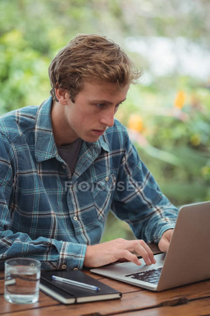 Человек сидит за столом и использует ноутбук дома — стоковое фото